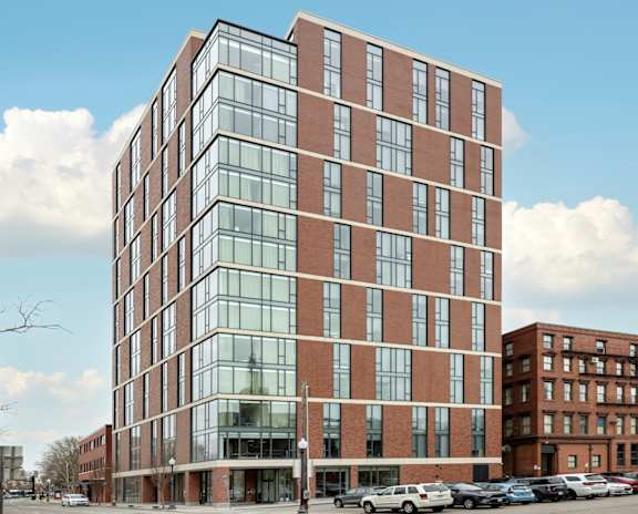 A modern glass and brick building stands tall in an urban setting.