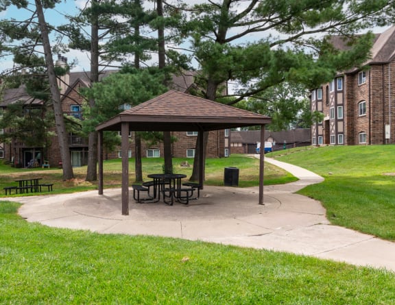 a picnic area with a gazebo in front of an apartment building