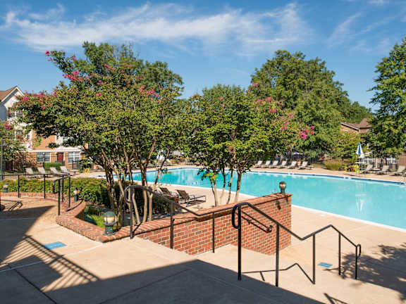 A pool surrounded by trees and a brick wall.