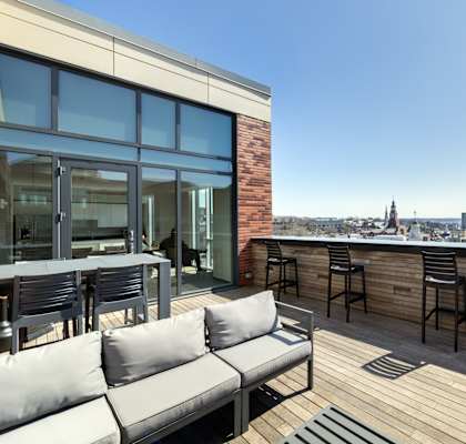 A rooftop patio with a couch, chairs, and a table.