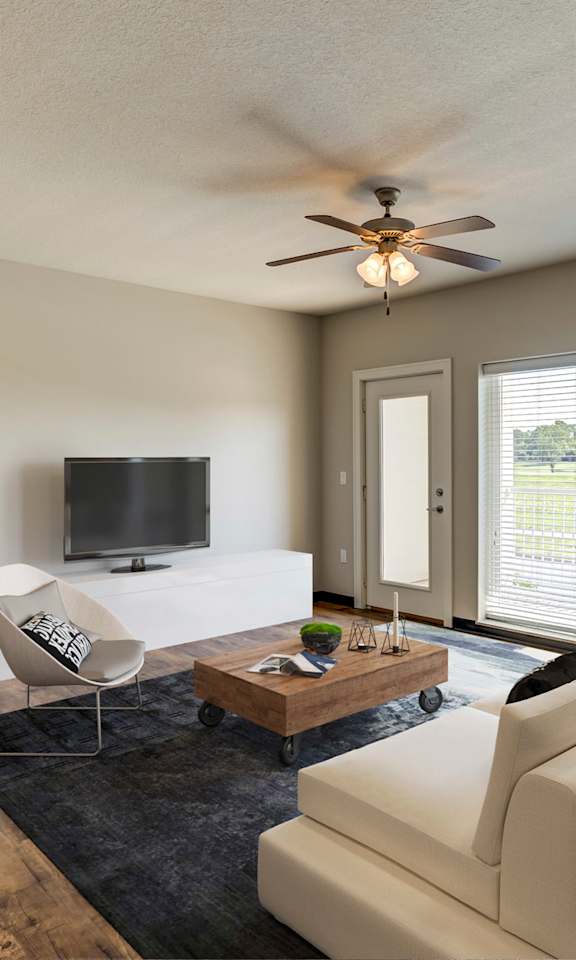 A living room with a white couch, a television, and a ceiling fan.
