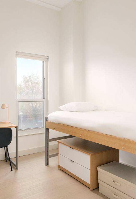 A room with a bed, desk, and chair.