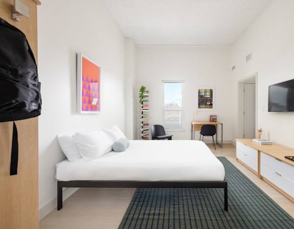 A bedroom with a bed, desk, and chair.