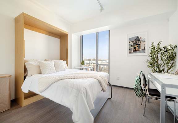 A bedroom with a large bed and a desk with a chair.