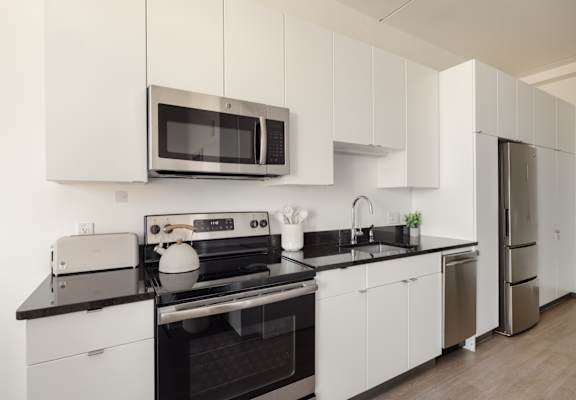 A modern kitchen with white cabinets and black countertops.