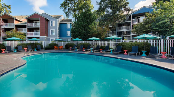 a swimming pool with lounge chairs and umbrellas in front of a building