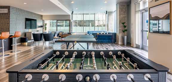 A foosball table is in the middle of a room with a couch and chairs.