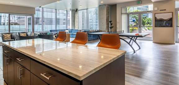 A modern kitchen with a long counter and orange chairs.