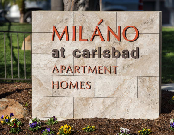 a large stone sign that reads milano at carlsbad apartment homes