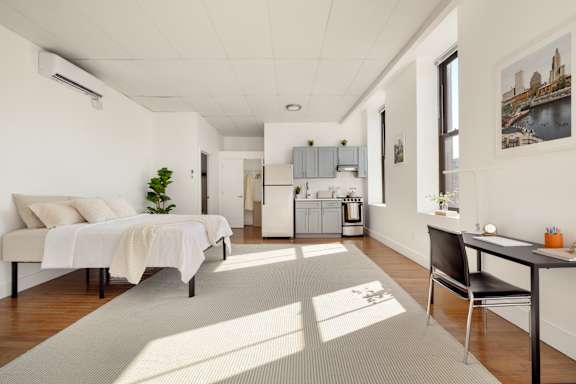 A well-lit room with a bed, a desk, and a chair.