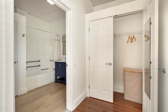 A white door is open to a room with a wooden floor and a white wall.