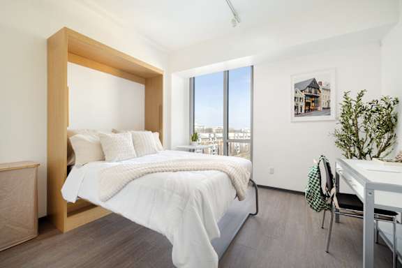 A bedroom with a large bed and a desk with a chair.