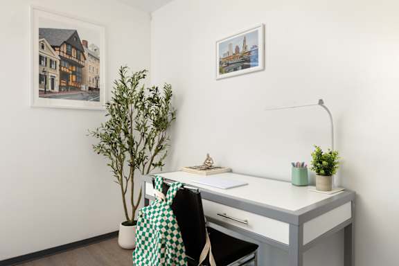 A room with a desk, chair, and two pictures on the wall.