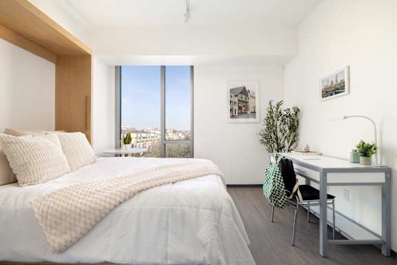 A bedroom with a large bed and a desk with a chair.