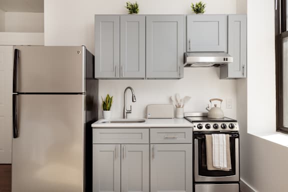 A kitchen with a refrigerator, sink, oven, and cabinets.