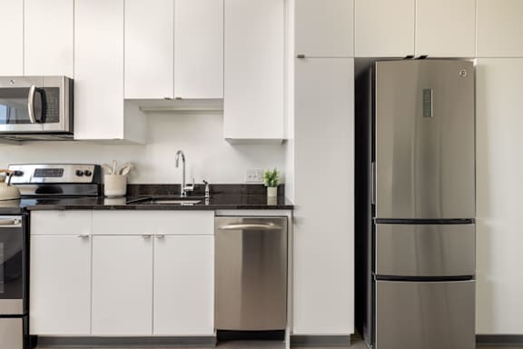 A modern kitchen with a stainless steel refrigerator and white cabinets.