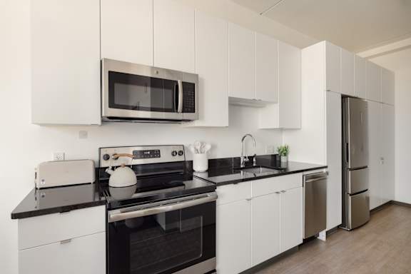 A modern kitchen with white cabinets and black countertops.