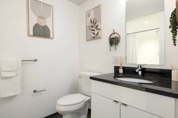 A bathroom with a toilet, sink, and mirror.