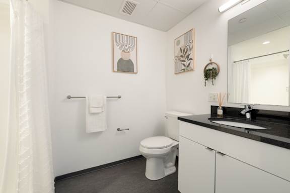 A white toilet sits in a bathroom next to a sink.