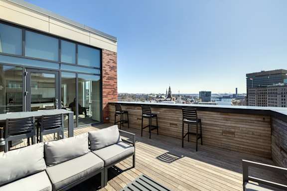 A rooftop patio with a couch, chairs, and a table.