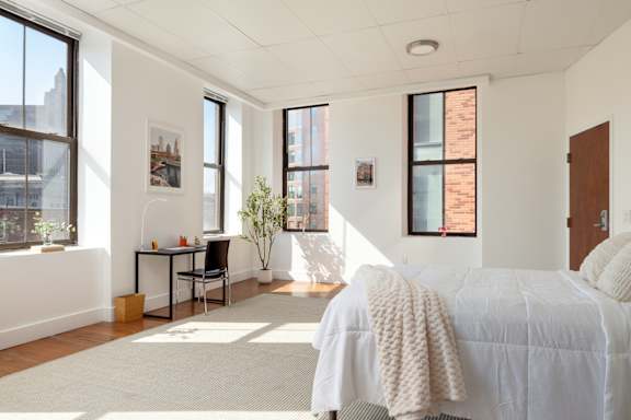 A bedroom with a bed, desk, and chair.