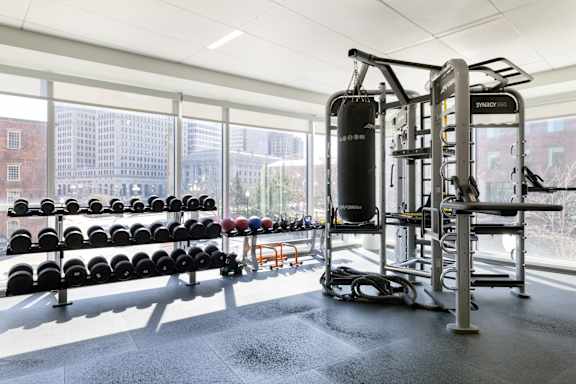 A gym with a row of black weight plates and a punching bag.