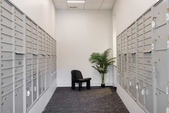 A room with a wall of mailboxes and a chair in the middle.