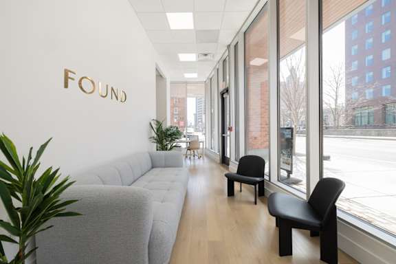 A long hallway with a couch, chairs and a plant.