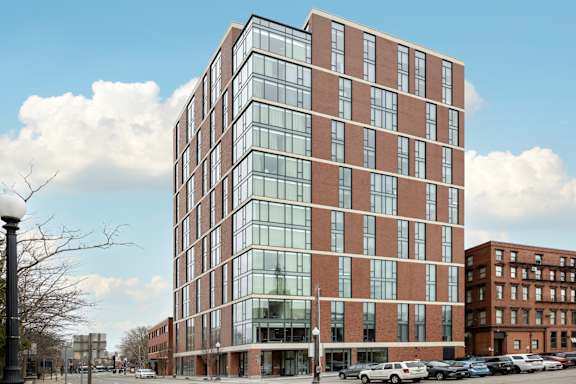 A modern glass and brick building stands tall in an urban setting.