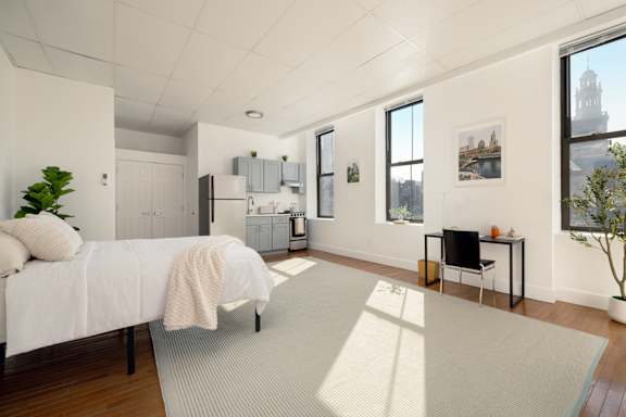 A bedroom with a bed, a chair, and a potted plant.