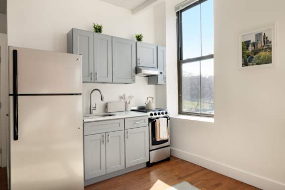 A kitchen with a refrigerator, sink, and stove.