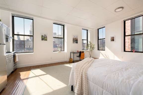 A bedroom with a large bed and a kitchen area.