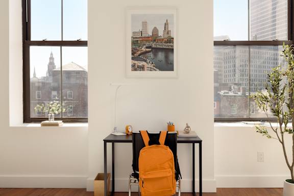 A room with a desk, chair and a picture on the wall.