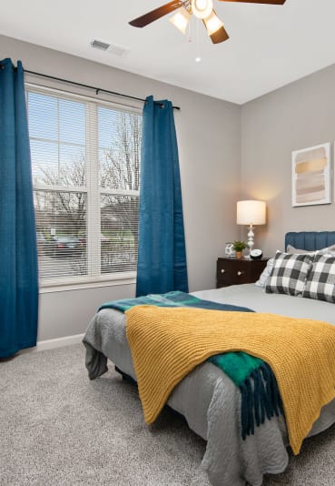 Comfortable Bedroom with Blue Curtains, Large Windows, and Grey Carpeting at Thornberry Woods Apartment Homes in Naperville, Illinois, 60565