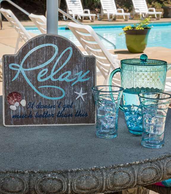 A table with a sign that says "Relax" and some glasses on it.