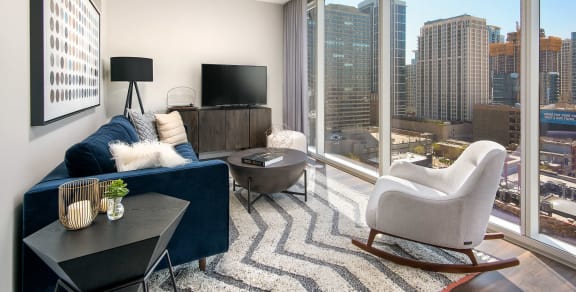 Living Room with a Blue Couch and Floor to Ceiling Windows with a City View at Eleven40 in Chicago, Illinois, 60605