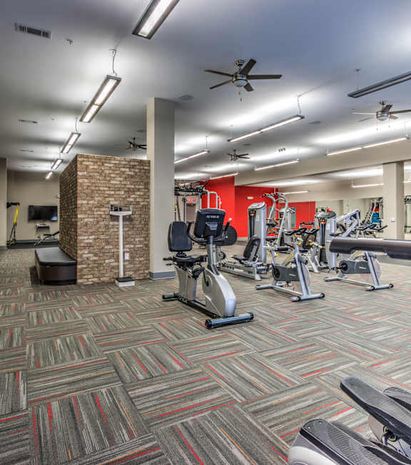 A gym with a variety of exercise equipment including treadmills, elliptical machines, and weights A gym with a variety of exercise equipment including treadmills, elliptical machines, and weights at Highland Row Apartments, Tennessee
