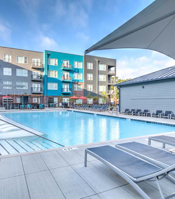 A swimming pool area with sun loungers and a building in the background. A swimming pool area with sun loungers and a building in the background at Highland Row Apartments, Memphis
