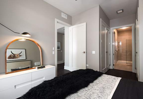 a bedroom with a bed and a mirror and a hallway with a closet
