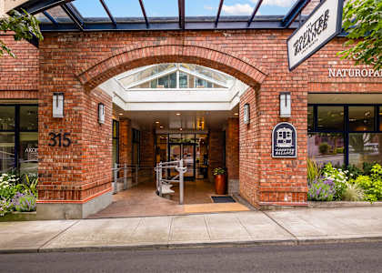 The entrance to a building with a glass roof and a brick facade.