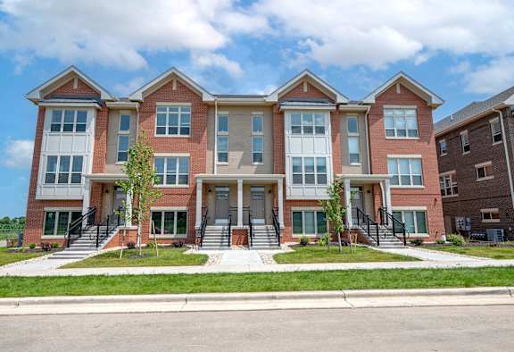 an apartment building with stairs and grass in front of it