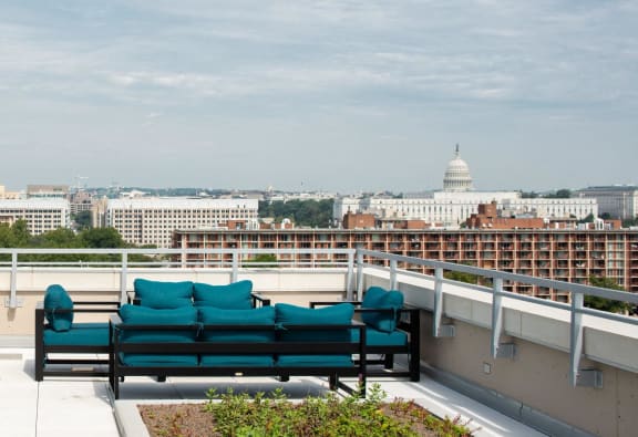 A bench with green cushions is on a balcony overlooking a cityscape. at Artline Apartments, Washington, DC
