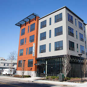 A modern multi-story building with a mix of orange and grey exterior.