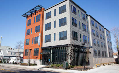 A modern multi-story building with a mix of orange and grey exterior.