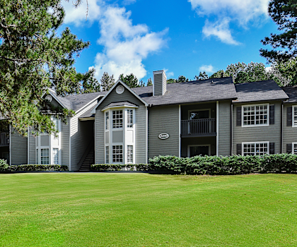 A large house with a grey roof and a green lawn in front.