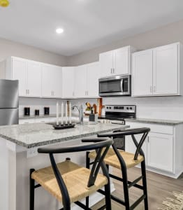 an open kitchen with a island with stools and a stainless steel refrigerator at Claret Village at LaFayette Trail, Tallahassee, FL
