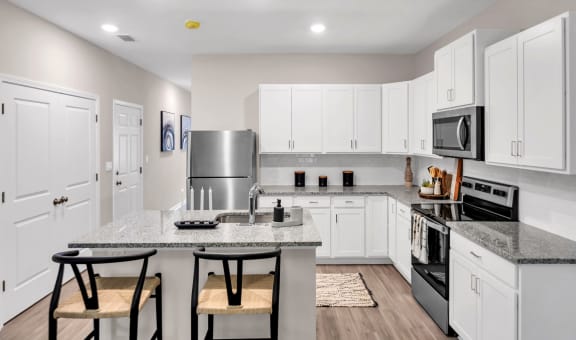 a large kitchen with white cabinets and stainless steel appliances at Claret Village at LaFayette Trail, Florida