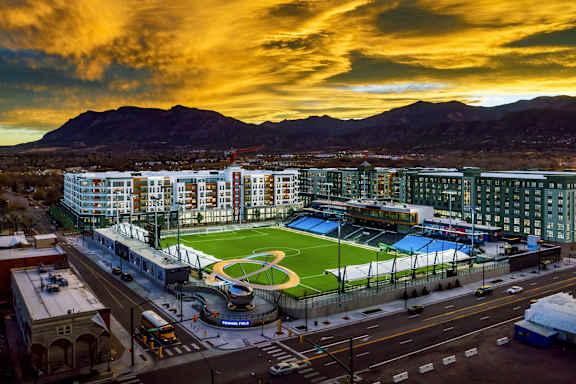 an aerial view of a soccer field in a city at sunset