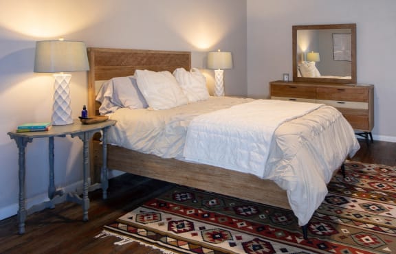 a bedroom with a bed, furnishings, and lamps and a rug at Goodall-Brown Lofts