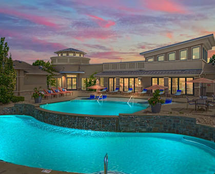 a swimming pool at a hotel with a sunset in the background